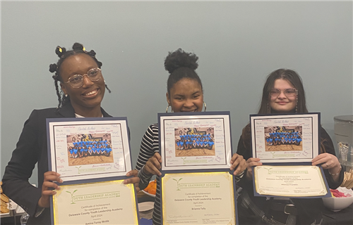 photo of three female students dressed professionally, holding up certificates